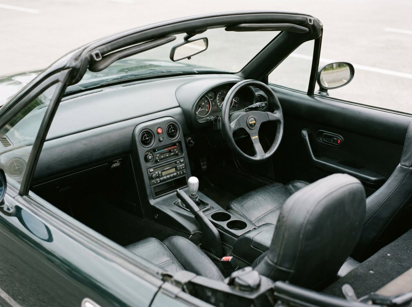 Intérieur Mazda MX-5 NA : cockpit noir minimaliste, petit volant Momo et levier de vitesses court