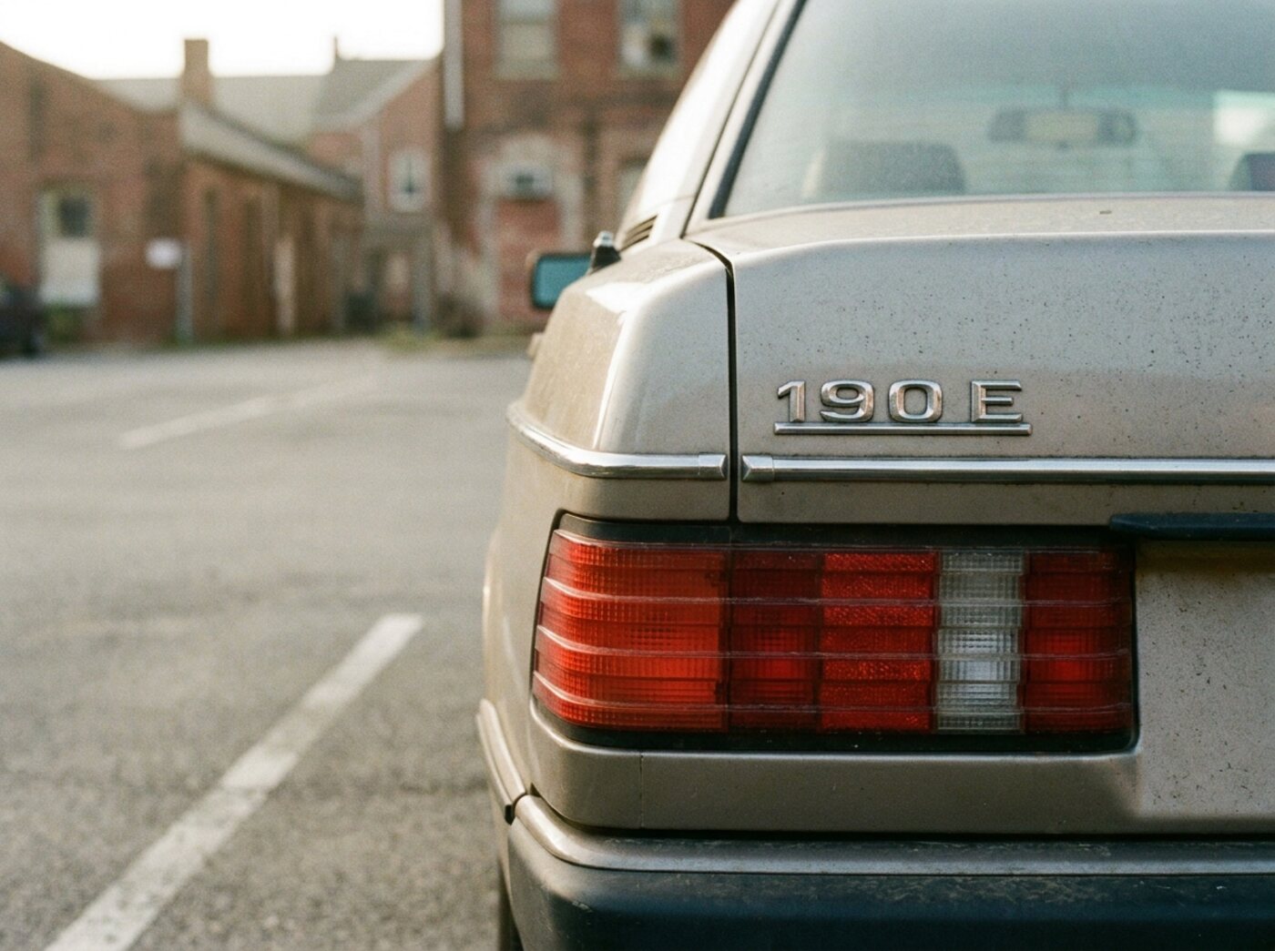 Détail arrière Mercedes 190E : feux striés et malle chromée avec monogramme 190 E